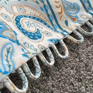 Decorative rug with intricate patterns and fringes on a textured surface