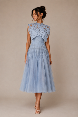 A woman models a light blue midi dress featuring a textured lace high-neck bodice overlay and a voluminous tulle skirt, set against a plain beige studio background.
