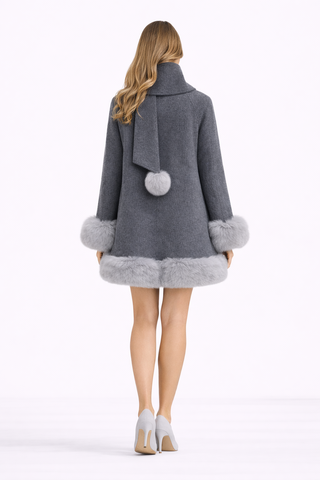 Woman wearing a gray coat with pom-pom details on a white background