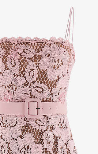 Close-up of a light pink lace camisole top with floral lace detailing, thin spaghetti straps, and a matching pink faux-leather belt with a square buckle.