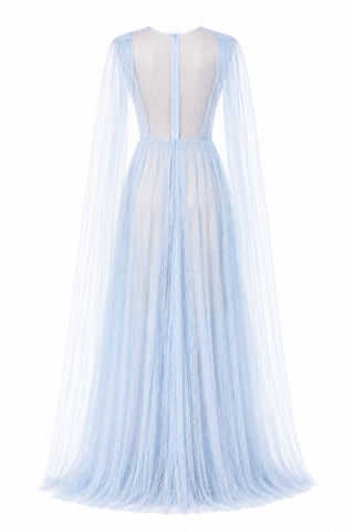 A light blue tulle maxi dress shown from the back, featuring a sheer mesh back panel, long draped cape sleeves, and a full flowing skirt on a white background.
