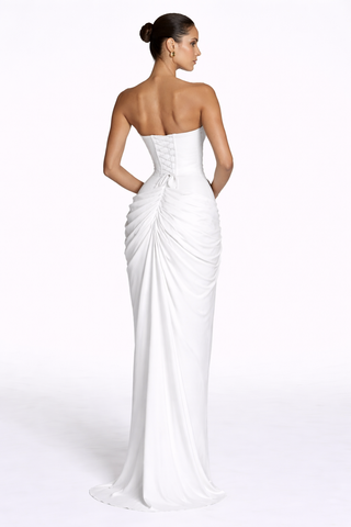 Woman wearing a strapless white gown with a draped design on a white background
