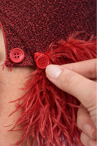 Close-up of a red dress with feather details and buttons.