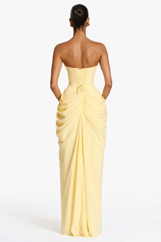 Yellow strapless gown with draped design on a white background