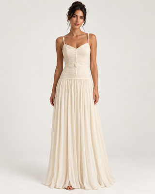 A woman modeling a floor-length cream or ivory spaghetti-strap dress with a structured corset-style bodice and a flowing skirt, photographed against a plain light gray studio background.