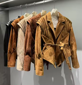 Premium wild leather goatskin suede jackets with pleated shoulder detailing, available in tan, rust brown, beige, and black, hanging on a clothing rack with adjustable belted waists for a tailored fit. Drejani Leather Jacket Suede, Wildleather Jacket