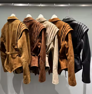 Premium wild leather goatskin suede jackets with pleated shoulder detailing, available in tan, rust brown, beige, and black, hanging on a clothing rack with adjustable belted waists for a tailored fit. Drejani Leather Jacket Suede, Wildleather Jacket