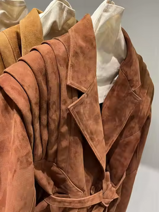 Premium wild leather goatskin suede jackets with pleated shoulder detailing, available in tan, rust brown, beige, and black, hanging on a clothing rack with adjustable belted waists for a tailored fit. Drejani Leather Jacket Suede, Wildleather Jacket