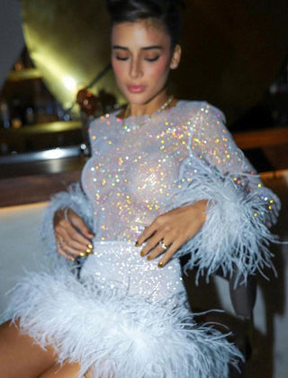Woman wearing a sparkling dress with feathered sleeves in an indoor setting