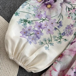 Romantic floral mini dress featuring a watercolor floral print in pink, lavender, lilac, and ivory tones, high neckline, long sleeves, matching waist belt, fit and flare silhouette, and flowing lightweight fabric, perfect for wedding guests, baby showers, bridal showers, garden parties, brunches, and elegant spring or summer occasions.