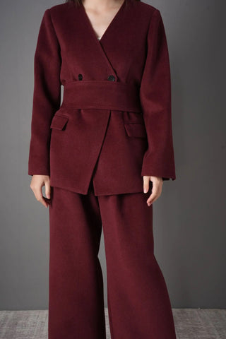 Model wearing the burgundy wool blazer and pants set, styled for a chic professional look with a black chain strap bag.