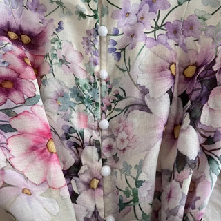 Close-up of a floral fabric with pink, purple, and green flowers.