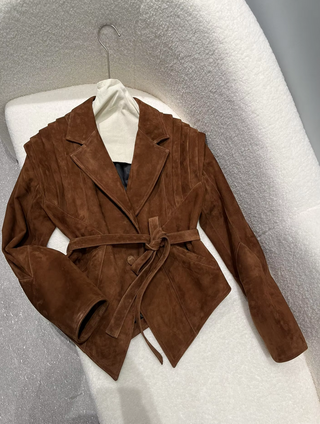 Premium wild leather goatskin suede jackets with pleated shoulder detailing, available in tan, rust brown, beige, and black, hanging on a clothing rack with adjustable belted waists for a tailored fit. Drejani Leather Jacket Suede, Wildleather Jacket