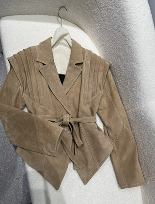 Premium wild leather goatskin suede jackets with pleated shoulder detailing, available in tan, rust brown, beige, and black, hanging on a clothing rack with adjustable belted waists for a tailored fit. Drejani Leather Jacket Suede, Wildleather Jacket