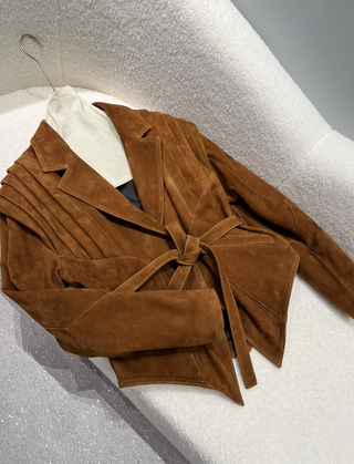 Premium wild leather goatskin suede jackets with pleated shoulder detailing, available in tan, rust brown, beige, and black, hanging on a clothing rack with adjustable belted waists for a tailored fit. Drejani Leather Jacket Suede, Wildleather Jacket