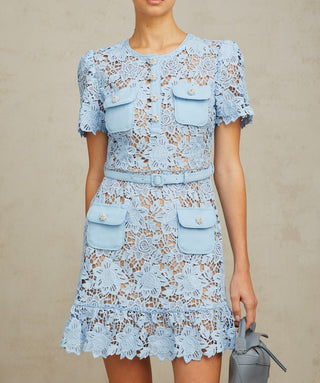 Model wearing Isola baby blue guipure lace mini dress with floral appliqué and belted waist