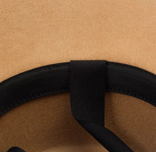 Close-up of a brown hat with a black band on a beige background