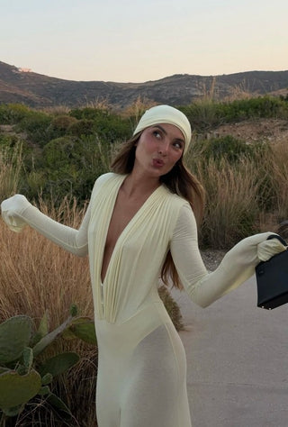 Woman in a white dress and gloves standing in a desert landscape