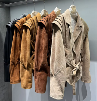 Premium wild leather goatskin suede jackets with pleated shoulder detailing, available in tan, rust brown, beige, and black, hanging on a clothing rack with adjustable belted waists for a tailored fit. Drejani Leather Jacket Suede, Wildleather Jacket