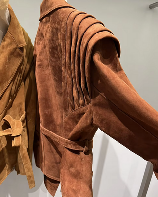 Premium wild leather goatskin suede jackets with pleated shoulder detailing, available in tan, rust brown, beige, and black, hanging on a clothing rack with adjustable belted waists for a tailored fit. Drejani Leather Jacket Suede, Wildleather Jacket Real Leather