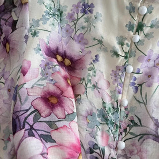 Romantic floral mini dress featuring a watercolor floral print in pink, lavender, lilac, and ivory tones, high neckline, long sleeves, matching waist belt, fit and flare silhouette, and flowing lightweight fabric, perfect for wedding guests, baby showers, bridal showers, garden parties, brunches, and elegant spring or summer occasions.