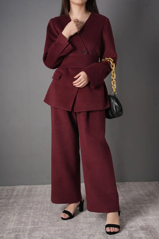 Model wearing the burgundy wool blazer and pants set, styled for a chic professional look with a black chain strap bag.