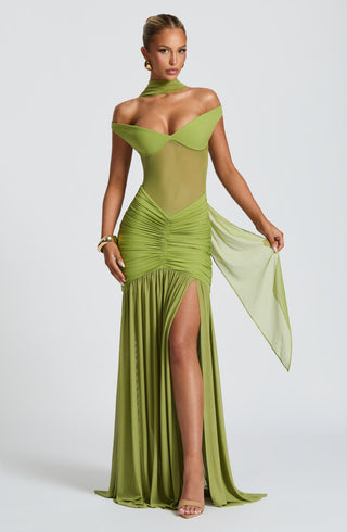 Woman wearing a green evening gown with a slit on a white background