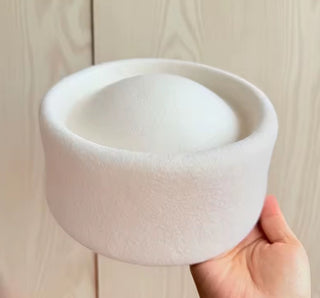 White ceramic bowl held by a hand against a light wooden background