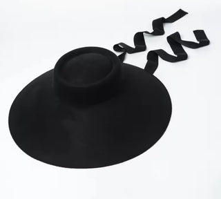 Black wide-brimmed hat with a ribbon on a white background
