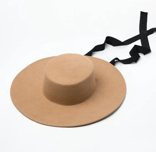 Beige wide-brimmed hat with a black ribbon on a white background