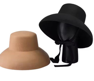 Two hats, one beige and one black, on a white background