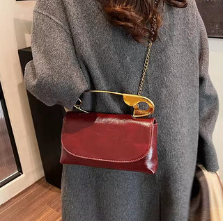 Person wearing a red handbag with a gold clasp