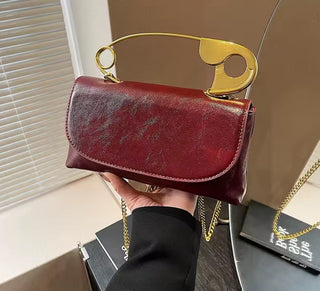 Red handbag with a gold handle held by a person, with a neutral background.