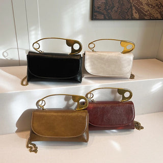 Four handbags in black, white, brown, and red with gold handles on a reflective surface.
