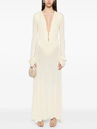 Woman wearing a long, light-colored dress with long sleeves on a white background