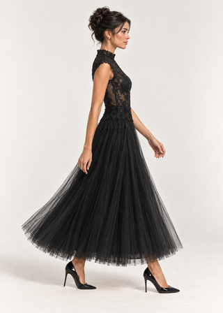 A woman modeling a black sleeveless midi dress with a lace bodice and a full tulle skirt, paired with black high heels, against a light gray studio background.