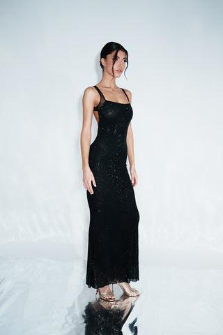 Woman wearing a black dress with thin straps on a white background