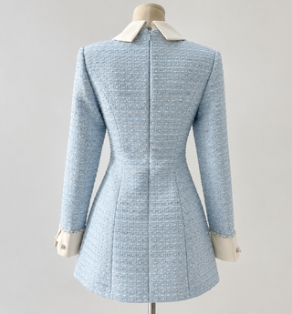 A light blue tweed jacket with a structured cream collar and cuffs, displayed on a dress form against a neutral light gray background.