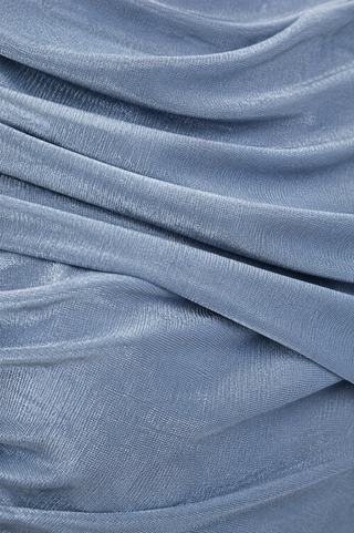 A close-up of draped dusty blue fabric with a fine textured weave.
