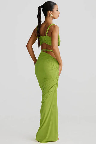 Woman wearing a green evening gown with a sheer top on a light gray background
