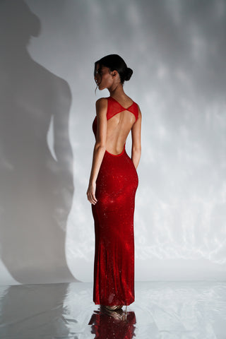 Woman wearing a red evening gown with a backless design against a gray background