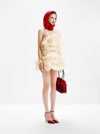 Woman wearing a cream dress with ruffles and a red headscarf and handbag on a white background