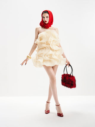 Woman in a cream dress with red accents holding a matching handbag on a white background