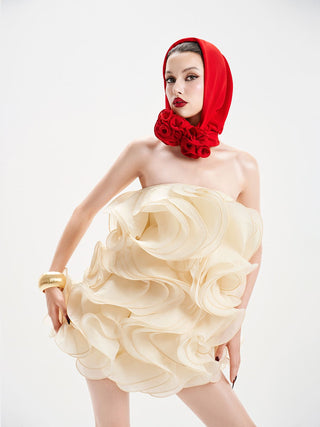 Woman wearing a cream strapless dress with a red headscarf and floral decorations on a white background
