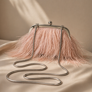 Pink feathered handbag with a long chain strap on a beige background