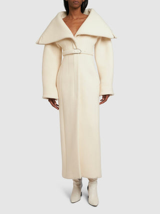 Person wearing a long cream coat on a white background