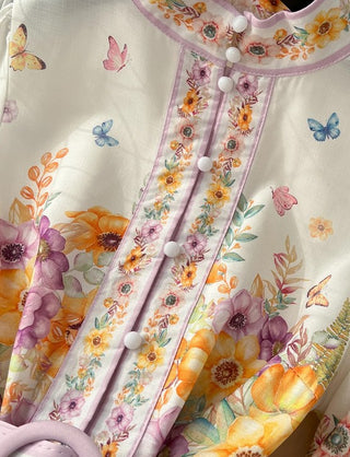 Close-up of a floral dress with colorful flowers and butterflies on a white background