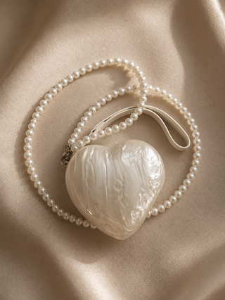 Heart-shaped pearl pendant on a beige fabric background
