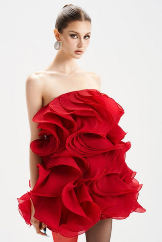 Woman wearing a red one-shoulder dress with ruffled details on a white background
