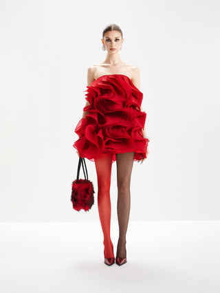 Woman wearing a red one-shoulder dress with ruffles on a white background